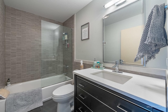 full bathroom featuring toilet, vanity, tile walls, and bath / shower combo with glass door