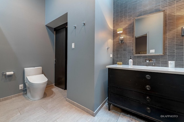 bathroom with tasteful backsplash, tile walls, vanity, and toilet