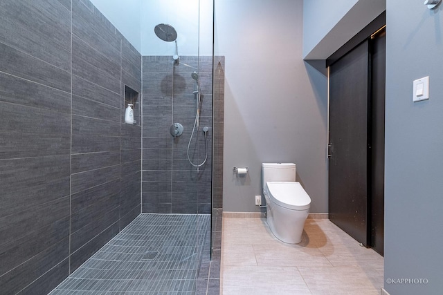 bathroom with toilet, a tile shower, and tile patterned floors