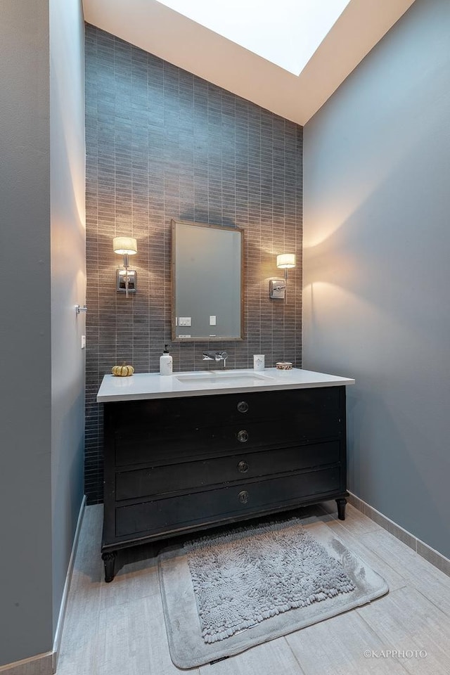 bathroom featuring tile walls, a skylight, and vanity