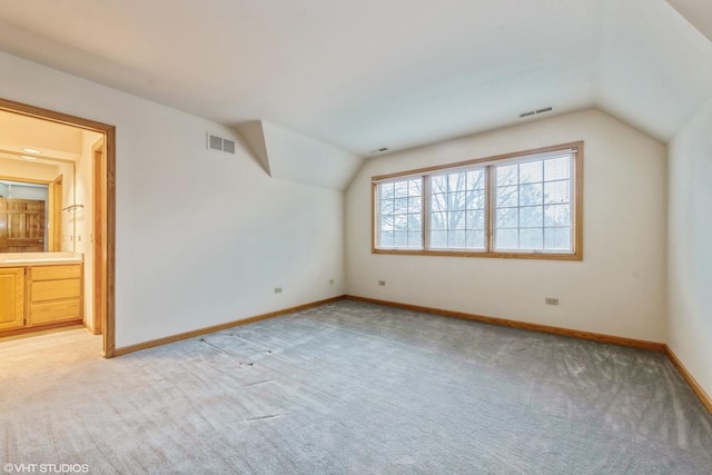 bonus room with light colored carpet and lofted ceiling