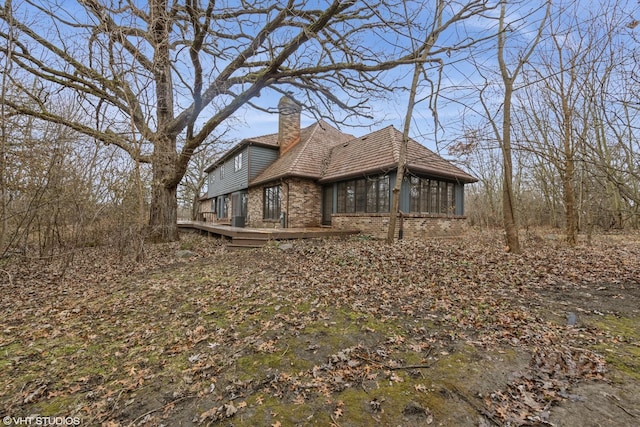 view of side of home with a wooden deck and a sunroom