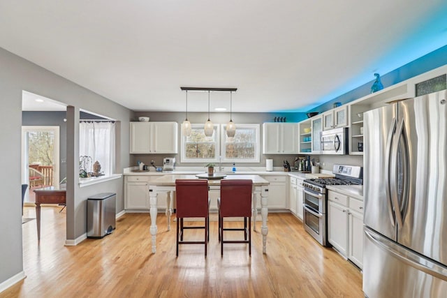 kitchen with white cabinetry, pendant lighting, stainless steel appliances, and a kitchen bar