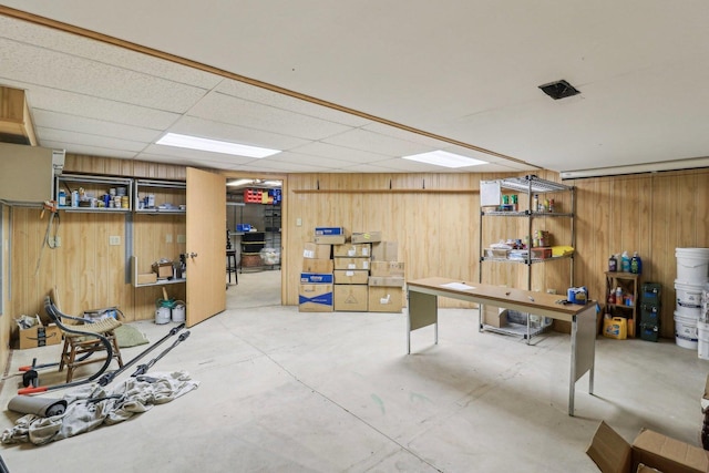 basement featuring a paneled ceiling and wooden walls