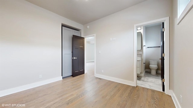 unfurnished bedroom with ensuite bath and light hardwood / wood-style flooring