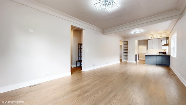 unfurnished living room with sink, light hardwood / wood-style floors, and ornamental molding