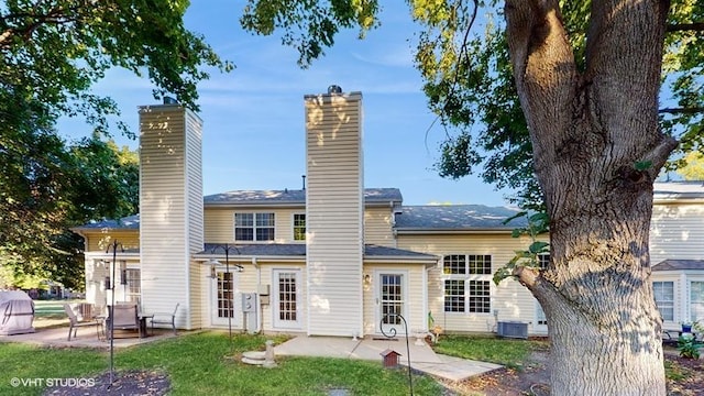 rear view of house with a patio, cooling unit, and a lawn