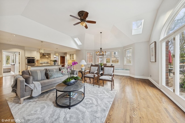 living room with plenty of natural light, ceiling fan with notable chandelier, and light wood-type flooring