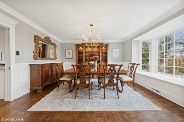 dining space with dark parquet flooring, crown molding, and an inviting chandelier