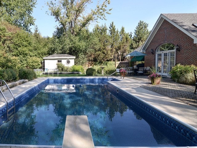 view of swimming pool with a diving board, french doors, and a patio