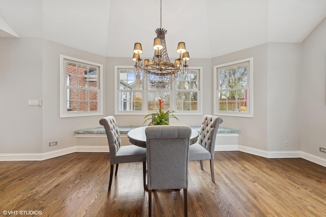 dining room with a notable chandelier, wood-type flooring, and lofted ceiling