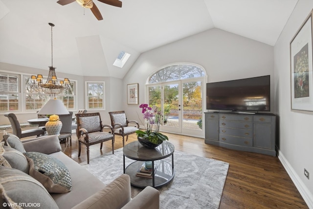 living room featuring dark hardwood / wood-style flooring, ceiling fan with notable chandelier, and vaulted ceiling with skylight