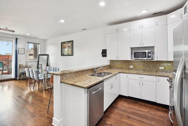 kitchen featuring stone counters, sink, stainless steel appliances, kitchen peninsula, and white cabinets