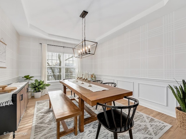 dining room featuring an inviting chandelier, light hardwood / wood-style flooring, and a tray ceiling