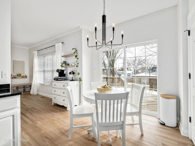 dining room with ornamental molding, light wood-type flooring, and a notable chandelier