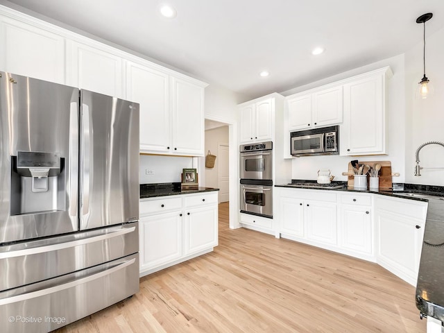 kitchen featuring appliances with stainless steel finishes, sink, pendant lighting, light hardwood / wood-style floors, and white cabinetry