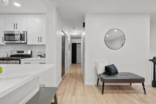 kitchen featuring backsplash, white cabinetry, light hardwood / wood-style flooring, and appliances with stainless steel finishes