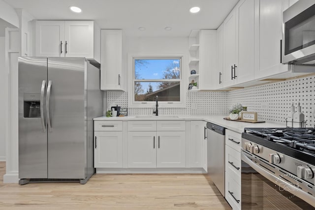 kitchen with light hardwood / wood-style flooring, stainless steel appliances, white cabinetry, and sink