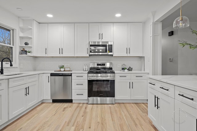 kitchen with appliances with stainless steel finishes, backsplash, white cabinetry, and sink