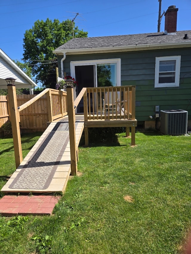 rear view of house featuring a lawn, central AC unit, and a deck