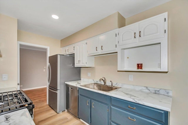 kitchen with white cabinets, blue cabinets, sink, light hardwood / wood-style flooring, and stainless steel appliances