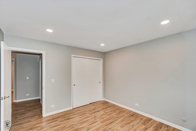 unfurnished bedroom with light wood-type flooring and a closet