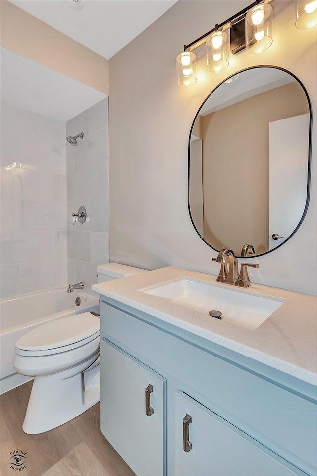 full bathroom with vanity, toilet, tiled shower / bath, and hardwood / wood-style flooring