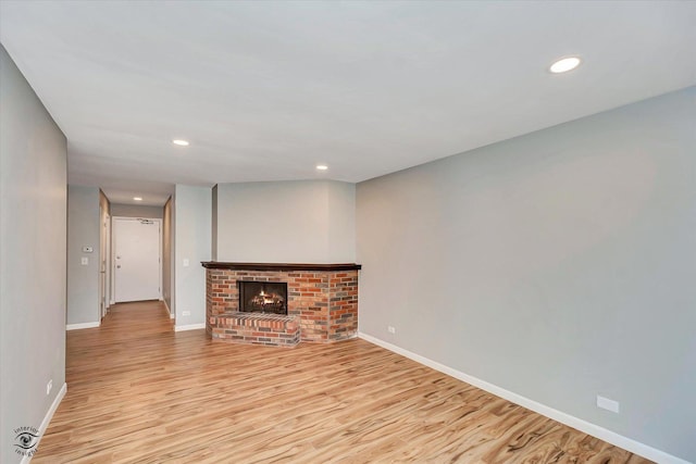 unfurnished living room featuring light hardwood / wood-style floors and a brick fireplace