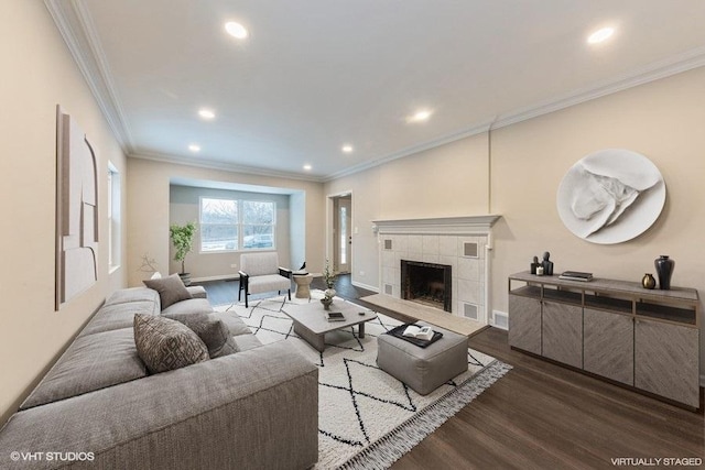 living room with a tile fireplace, crown molding, and dark hardwood / wood-style floors