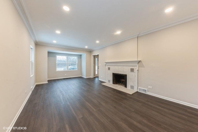 unfurnished living room with dark hardwood / wood-style floors, ornamental molding, and a tiled fireplace