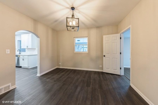 unfurnished room featuring sink, dark wood-type flooring, and an inviting chandelier