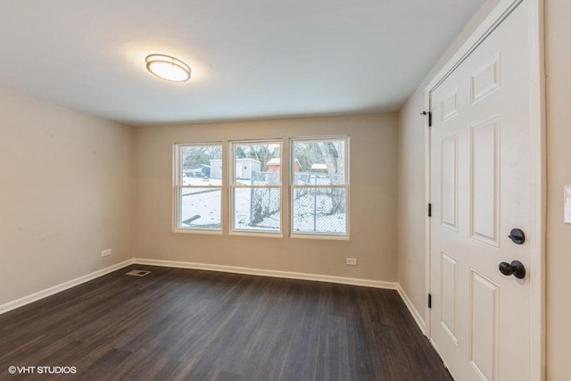 spare room featuring dark hardwood / wood-style flooring and a healthy amount of sunlight