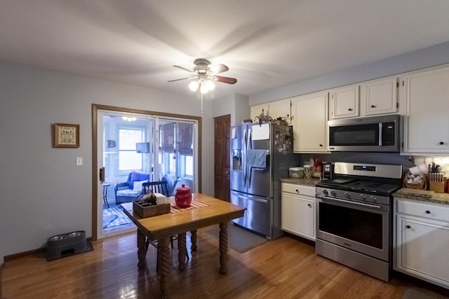 kitchen with white cabinets, light stone counters, dark wood-type flooring, and appliances with stainless steel finishes