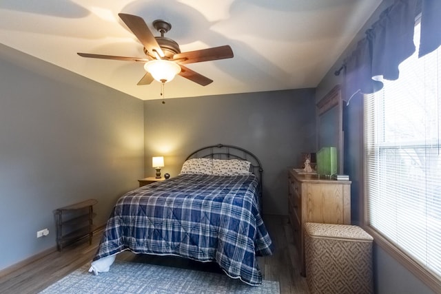 bedroom featuring multiple windows, hardwood / wood-style floors, and ceiling fan