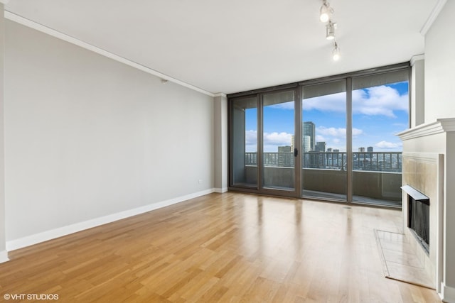 unfurnished living room with a tiled fireplace, light hardwood / wood-style floors, crown molding, and floor to ceiling windows