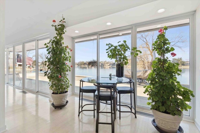 dining room with a healthy amount of sunlight, a water view, and a wall of windows