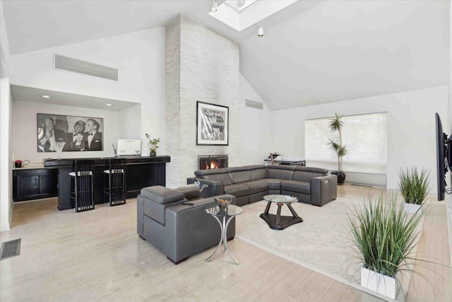 living room with hardwood / wood-style flooring, high vaulted ceiling, and a stone fireplace