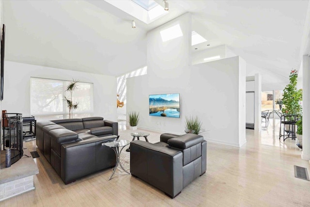 living room with a skylight, light hardwood / wood-style flooring, and high vaulted ceiling