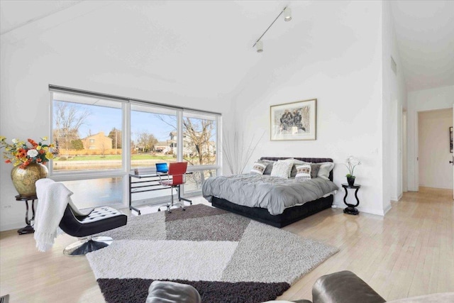 bedroom featuring a high ceiling, track lighting, and light wood-type flooring