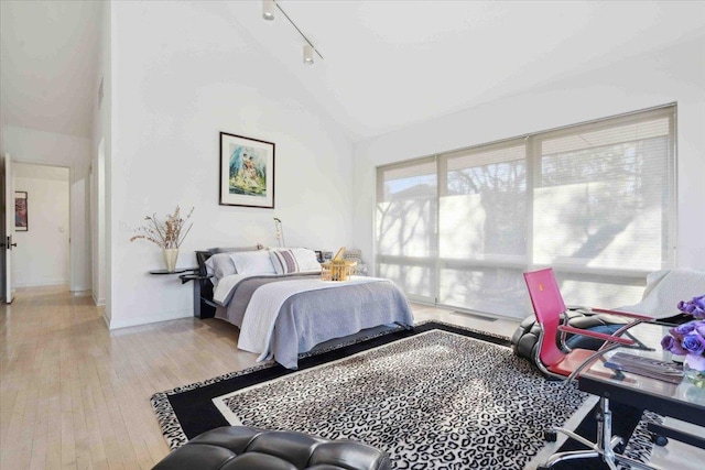 bedroom with multiple windows, high vaulted ceiling, and light hardwood / wood-style floors