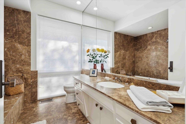 bathroom featuring vanity, tile walls, and toilet