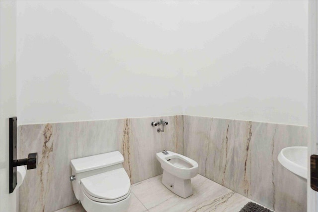 bathroom with a bidet, tile walls, and toilet