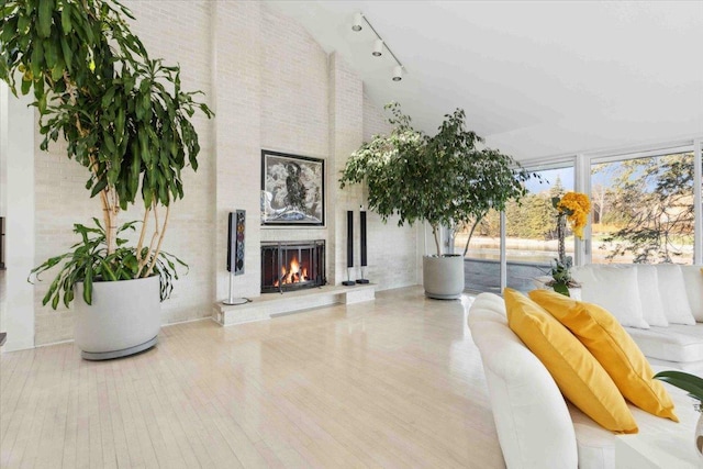 living area featuring hardwood / wood-style floors, track lighting, floor to ceiling windows, and a brick fireplace