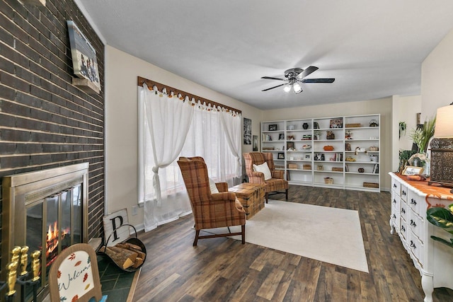 sitting room featuring ceiling fan, a fireplace, and dark wood-type flooring