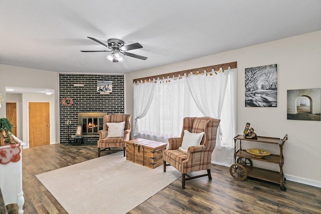 sitting room featuring dark hardwood / wood-style floors, ceiling fan, and a brick fireplace