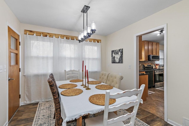 dining room with dark hardwood / wood-style floors, plenty of natural light, and a notable chandelier