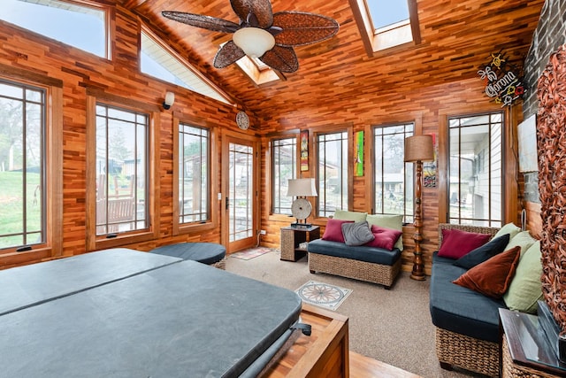 carpeted bedroom with a skylight, ceiling fan, high vaulted ceiling, wood walls, and wood ceiling