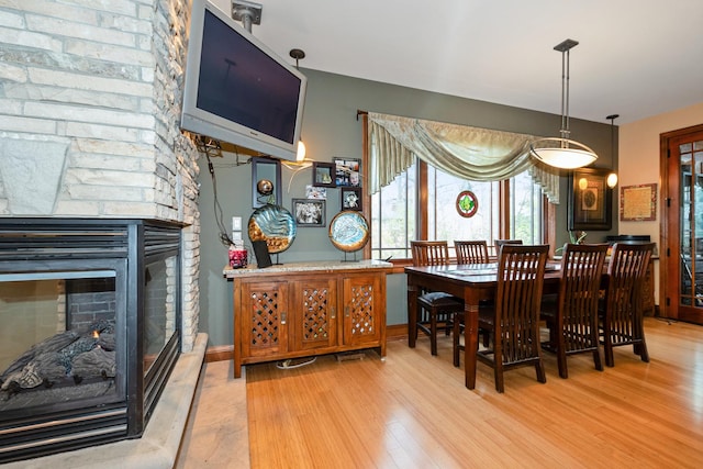 dining room with a stone fireplace and light wood-type flooring