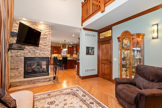 living room with a stone fireplace, light wood-type flooring, and ornamental molding