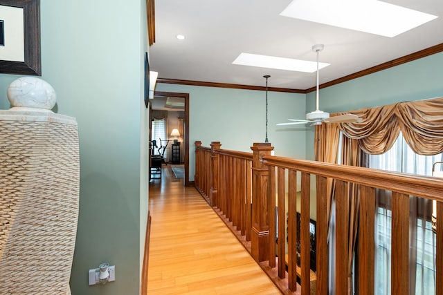 hallway with a skylight, crown molding, and light wood-type flooring